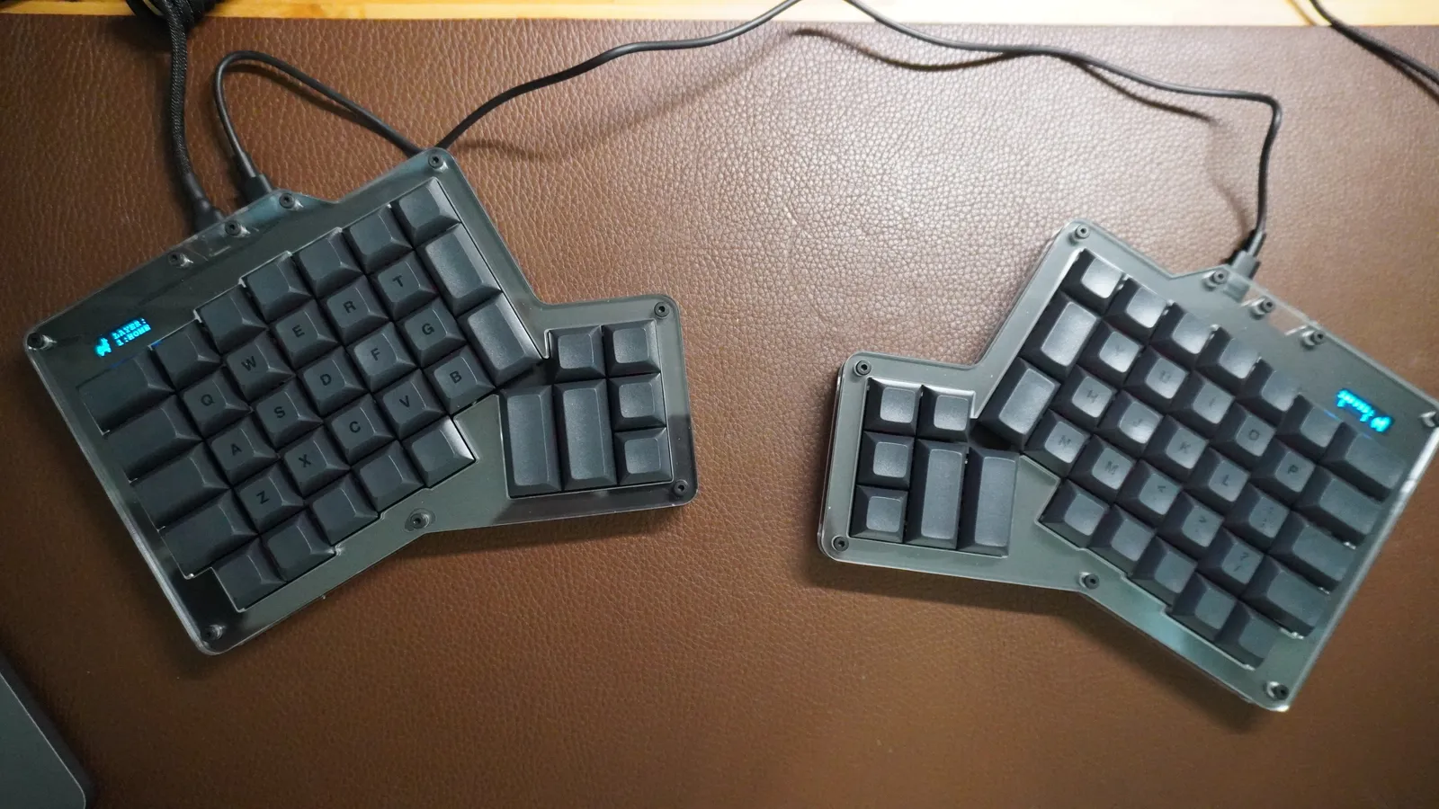 ErgoDox 76 Hot Dox V2 halves set apart on a leather desk mat, each with its own USB-C cable